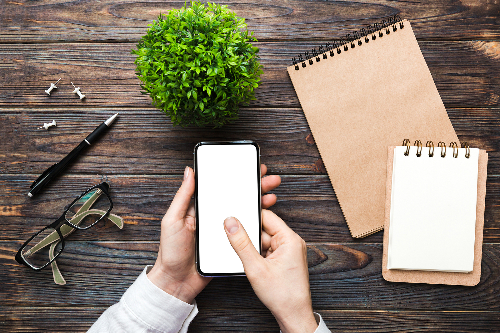 Top view of woman hands holding smart phone with blank copy space screen for your text message or information content. woman hand using phone white screen on top view.