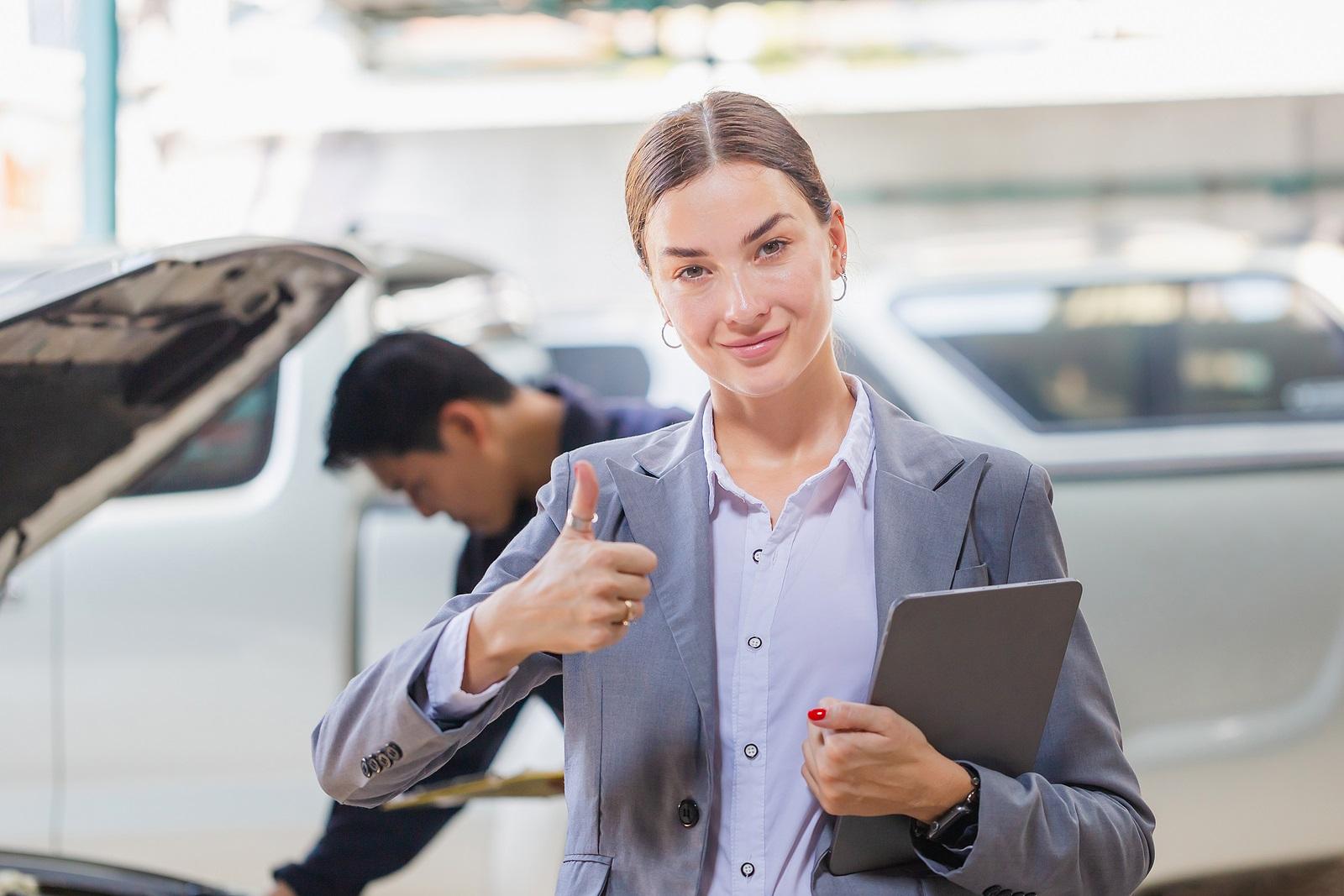 Female manager and car mechanic while working in auto repair shop, Young business woman with digital tablet showing thumbs up, Car repair, and maintenance concepts